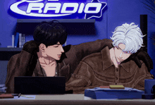 a couple of men sitting in front of a sign that says radio