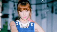 a woman with red hair is wearing a blue overalls and a necklace