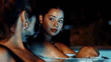 two women are sitting in a hot tub at night and one of them is looking at the camera .
