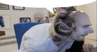 a bald man with long hair and headphones is sitting in a chair in front of a computer .