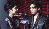 a couple of men are standing next to each other and one of them is holding a microphone .