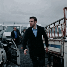 a man in a suit and a blue shirt is walking towards a white van