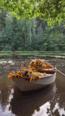 a boat filled with sunflowers is floating on a river