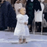 a little girl in a white dress is standing on a dance floor