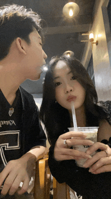 a man kisses a woman on the cheek while she drinks from a cup with a straw that says yja
