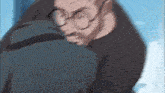 a man with glasses and a beard is hugging another man .