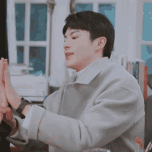 a man wearing a grey coat is giving a high five