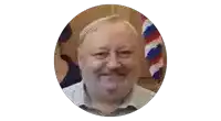 a man with a beard is smiling in a circle with a flag in the background