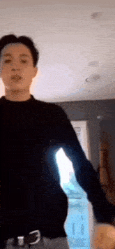 a young man in a black sweater is standing in a living room .