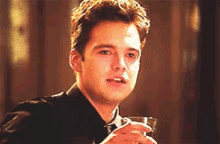 a young man in a suit and tie is holding a glass of wine .