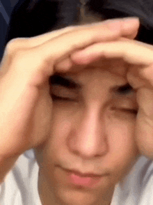 a young man is covering his face with his hands while making a funny face .