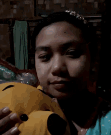a woman is holding a yellow stuffed animal with a black face