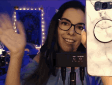 a woman wearing glasses and headphones is smiling and holding a cell phone