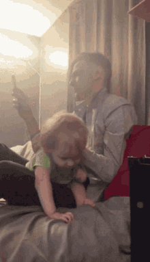 a man is playing with a baby who is crawling on his lap