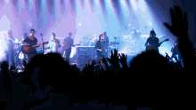 a group of people playing instruments on a stage with their hands in the air
