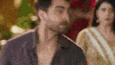 a man with a beard is standing in front of a woman in a gold dress .