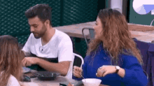 a man and a woman are sitting at a table eating food from bowls .