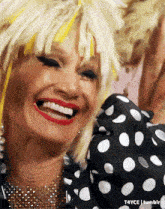 a close up of a woman wearing a wig and polka dot shirt smiling .