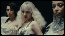 three women are standing next to each other with one wearing a white dress
