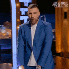 a man in a blue suit is standing in front of a sign that says ' this is smarter than celebrity '