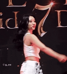 a woman in a white crop top and white shorts is dancing on a stage