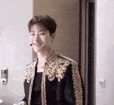 a young man wearing a black and gold jacket and a microphone smiles