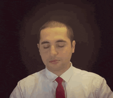 a man wearing a white shirt and black tie looks at the camera