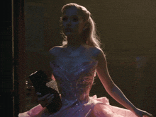 a woman in a pink dress holds a book in her hand