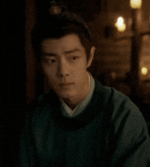 a man in a green shirt is looking down in a dark room .