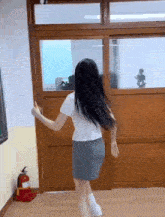 a girl in a school uniform is dancing in a room with a fire extinguisher on the floor .