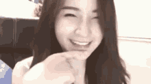 a woman with long hair is smiling and making a peace sign with her finger .