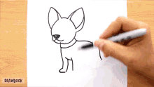 a person is drawing a chihuahua dog on a piece of paper