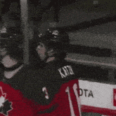 a hockey player wearing a canada jersey is talking to a referee
