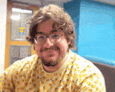 a man wearing glasses and a shirt with oranges on it smiles in front of a door that has a caution sign on it