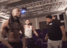 a group of men are dancing in a room with a purple couch