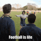 a group of people standing on a field with the words " football is life " written on the bottom