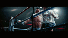 two boxers are fighting in a ring and one has a tattoo on his chest that says ' i love you '