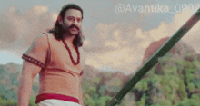 a man with a mustache is holding a spear with the hashtag avantika_0902 on the bottom right