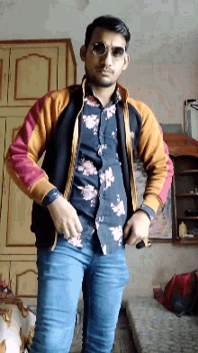 a man wearing a floral shirt and sunglasses stands in a room