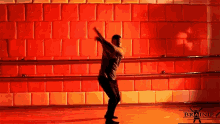 a man is dancing in front of a red wall that says brainif