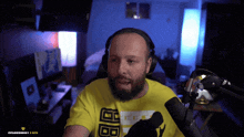 a man with a beard wearing headphones and a yellow t-shirt with the letters bb on it