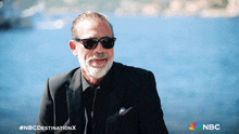 a man wearing sunglasses and a suit with the nbc destination x logo