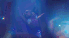 a woman in a bikini is laying on the floor in a dark room with blue lights behind her