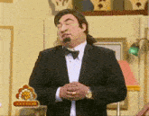 a man in a tuxedo and bow tie stands in front of a sign that says 1000000