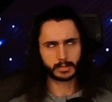 a man with long hair and a beard is making a funny face while sitting in a chair .