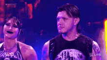 a man and a woman are standing next to each other on a stage in front of a purple background .