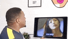 a man is looking at a picture of a woman on a tv screen .