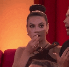 a woman in a bun is eating a candy bar while sitting in a theater .