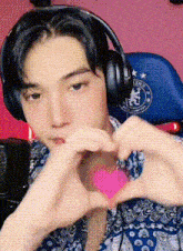 a young man wearing headphones making a heart shape with his hands
