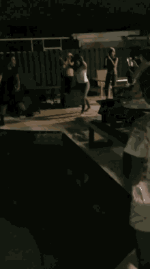 a swimming pool is lit up at night with a few chairs in the background